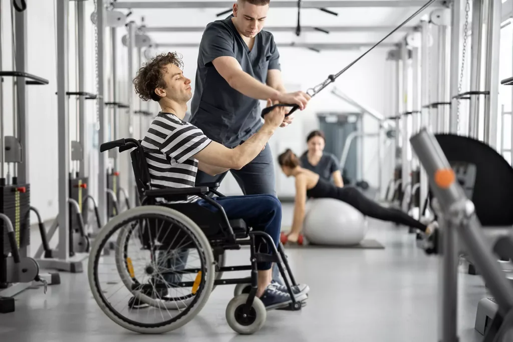 A disabled man sitting in his wheelchair and his personal trainer doing NDIS Personal Training