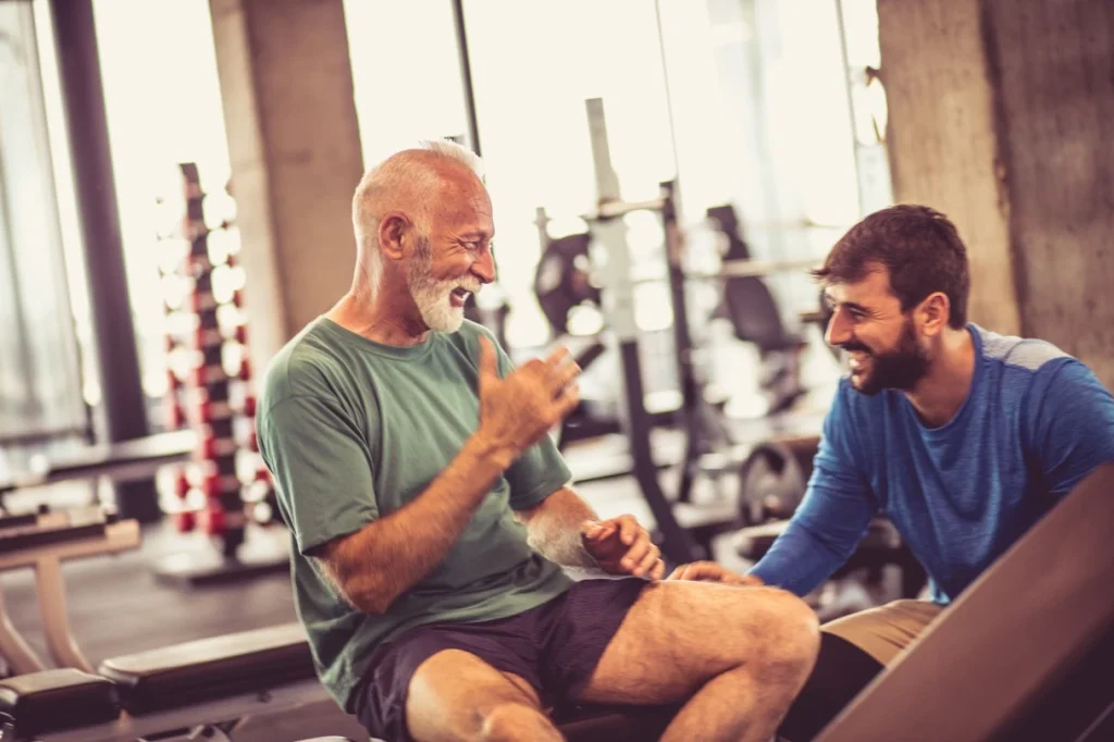 Elderly man and his trainer smiling at each other